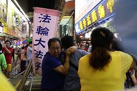 '图4：黑帮青关会头目林国安（左一，蓝衫者）勒住一名市民脖子，女恶霸肖小容（右一，黄衫者）则用脚狠踢，部份法轮功学员也被恶徒殴打。'