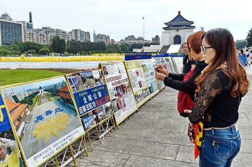 图11-12：大陆游客将法轮功学员排字盛况的真相展板内容照下，有的和展板合影，打算带回国内给亲友看。