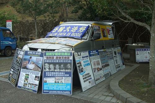 玄光寺停车场上摆满真相展板的车子，后座还有一台电视不断播放真相，常有游客停下脚步仔细观看。