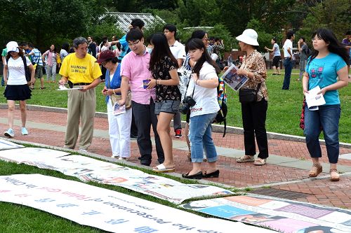 许多游客不但认真阅读讲述法轮功真相的图片，并与学员攀谈了解真相。