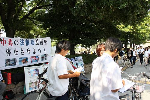 人们驻足观看真相展板，或和学员交谈了解真相