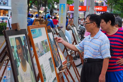 民众驻足观看法轮功真相展板