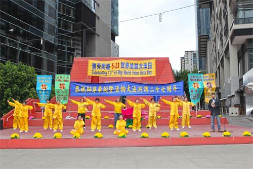 '图1：二零一九年五月十二日，墨尔本法轮功学员在市中心女王桥广场（Queensbridge Square）举行隆重庆典，恭贺第二十届“世界法轮大法日”和创始人李洪志先生华诞。图为学员们在展示功法。'