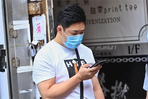 '图3：自称是摆放展示架老妇的儿子，全程在为老妇以手机拍照。'