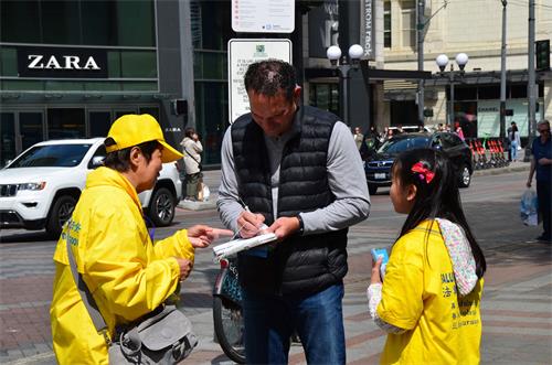 图3：法轮功学员和路人讲真相后，路人在呼吁结束中共迫害法轮功的请愿书上签名。